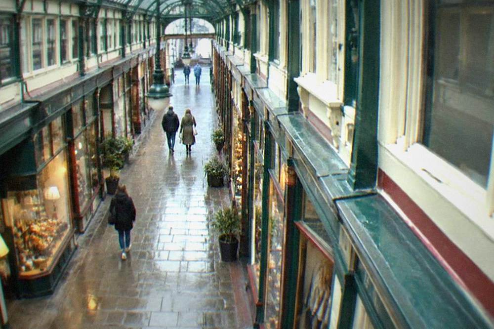 Victorian shopping arcade interior with small shopfronts under a glass roof