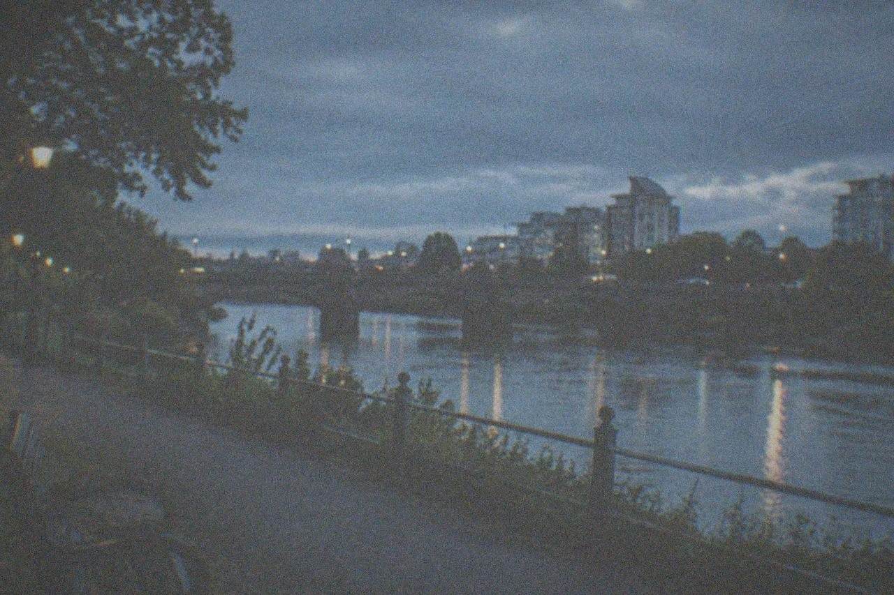 A riverside path beside a stone bridge in a green park