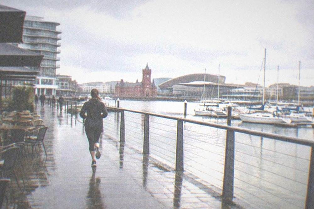 A waterfront terrace with tables and chairs overlooking boats moored in Cardiff Bay