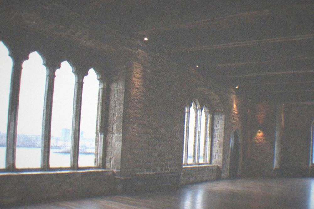 Stone castle interior hall with wooden beams and arched windows on a rainy day